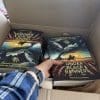 black banners box a hand reaching into a box of books under black banners