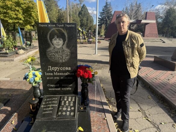 a woman standing next to a womans tombstone
