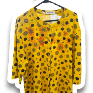 Yellow long-sleeve blouse with black polka dots and orange sunflower prints on a hanger, front view showing collar and button placket.