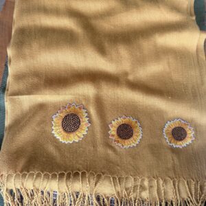 Mustard-yellow scarf with three embroidered sunflowers near the bottom edge and a fringed hem.
